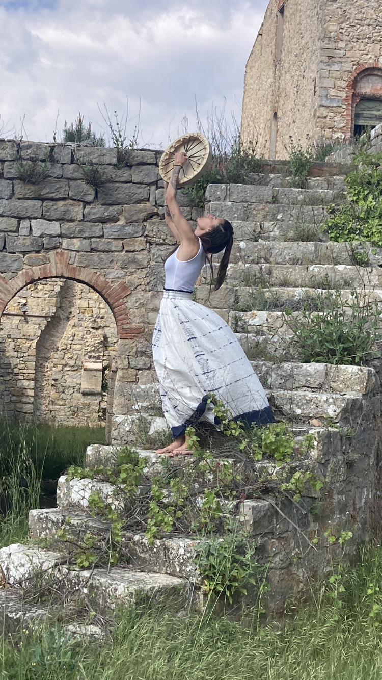 Chloé et son tambour chamanique sur un escalier de pierre dans une ruine